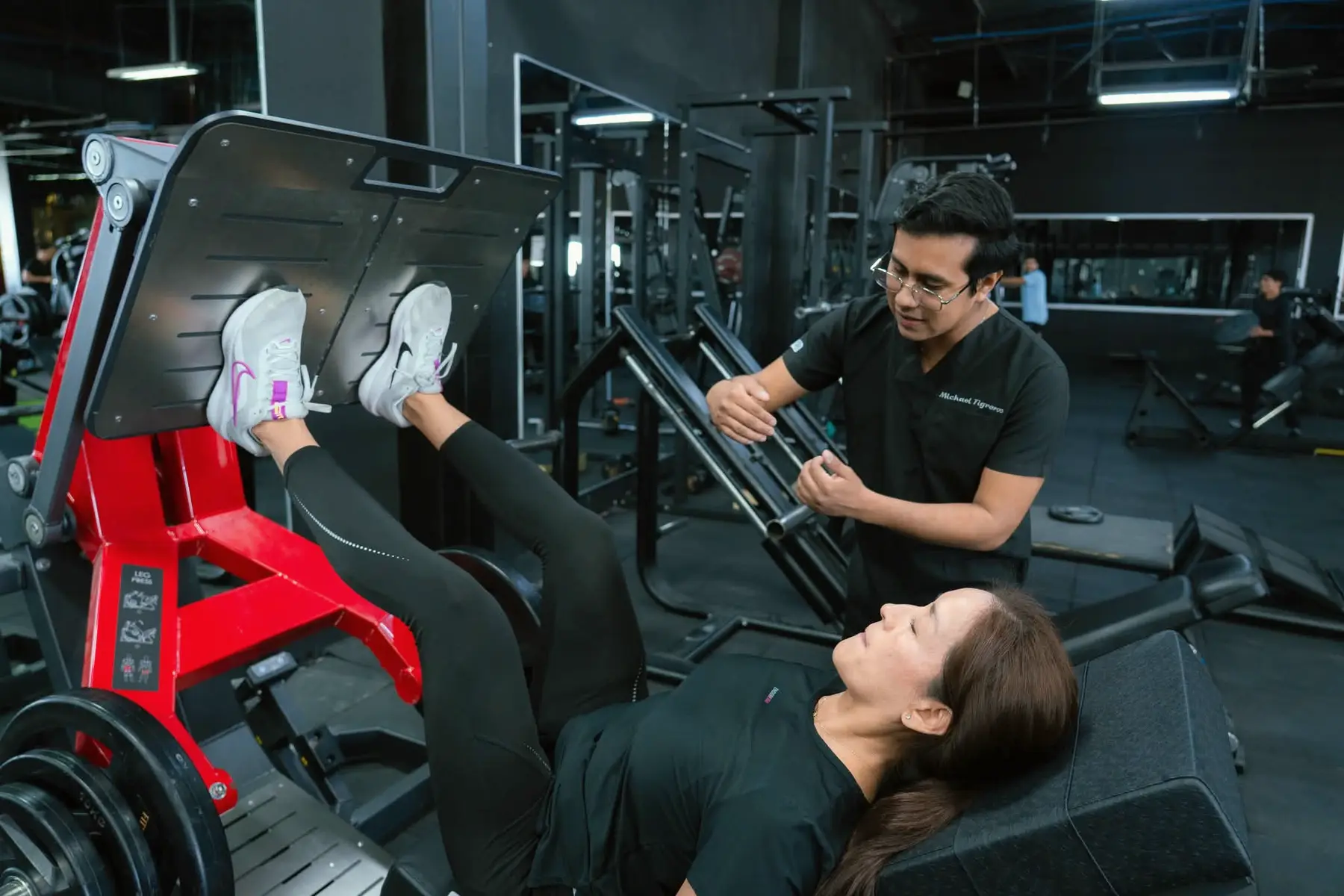 Mujer adulta en entrenamiento de fuerza funcional guiado por un entrenador