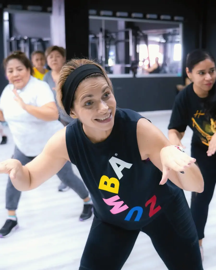 Adulta mayor disfrutando de una actividad en el gimnasio de Fisiosmart, con otras personas alrededor